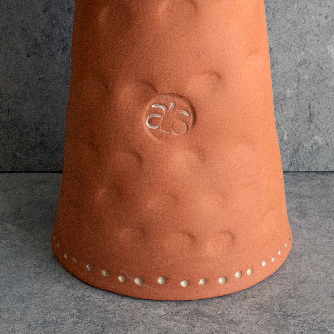 The ELEVATED TERRACOTTA BOWL is a handcrafted, multi-purpose ceramic piece with off-white glazing. Use as a centerpiece, fruit bowl, or floral display. Limited edition